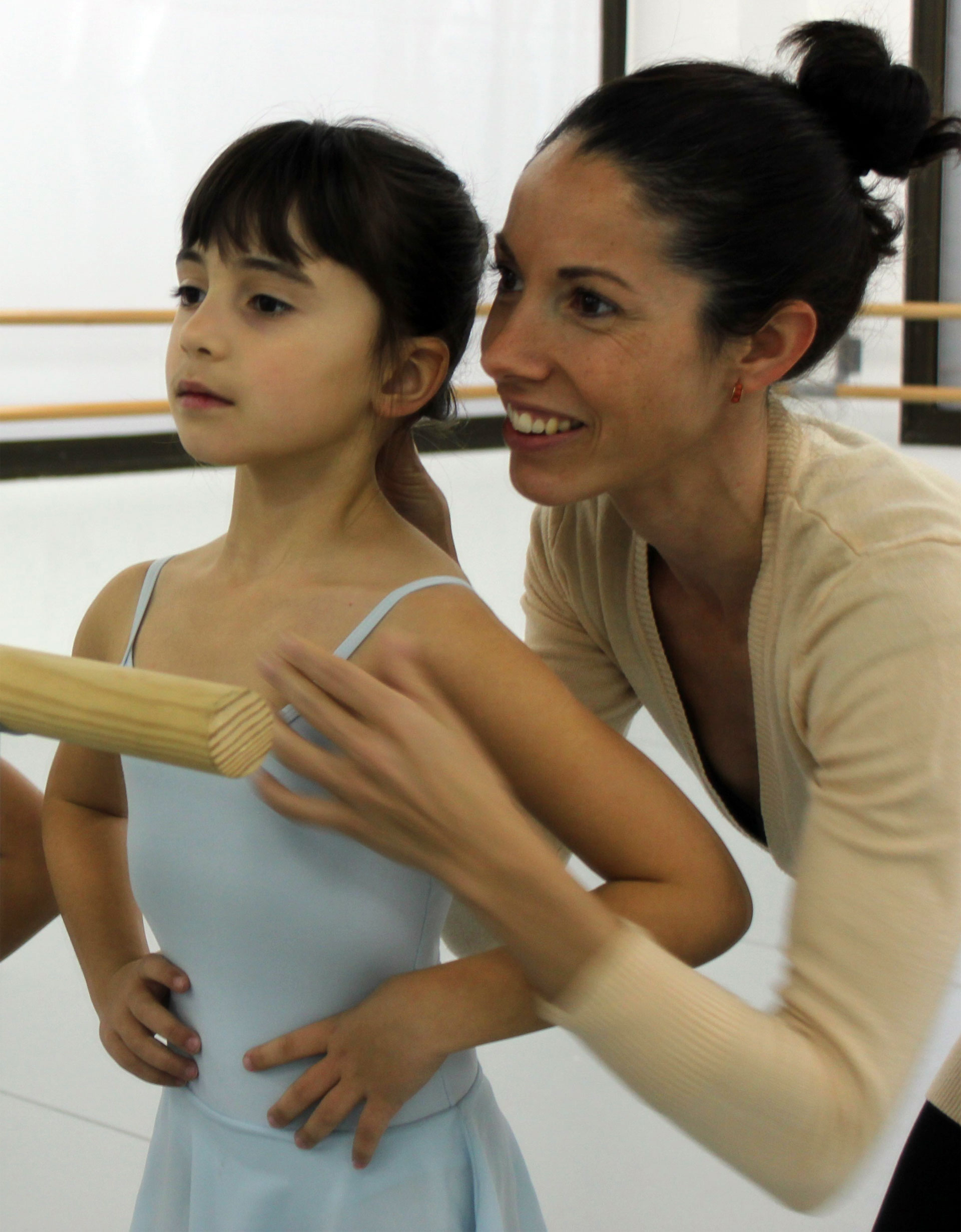 profesora corrigiendo postura de niña de preballet